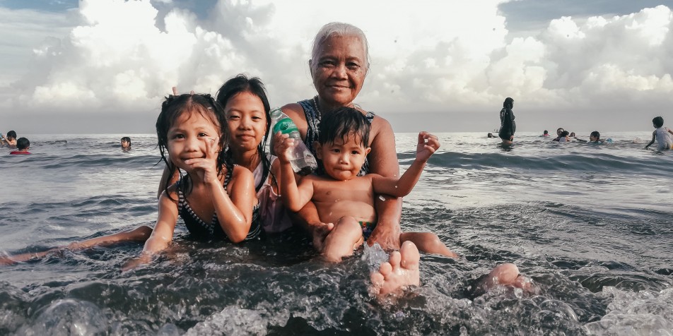 grandmother holding three children at beach