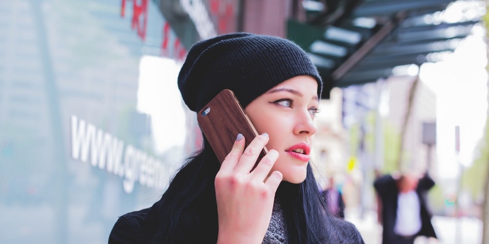 Young woman in hat holding cell phone to her ear.