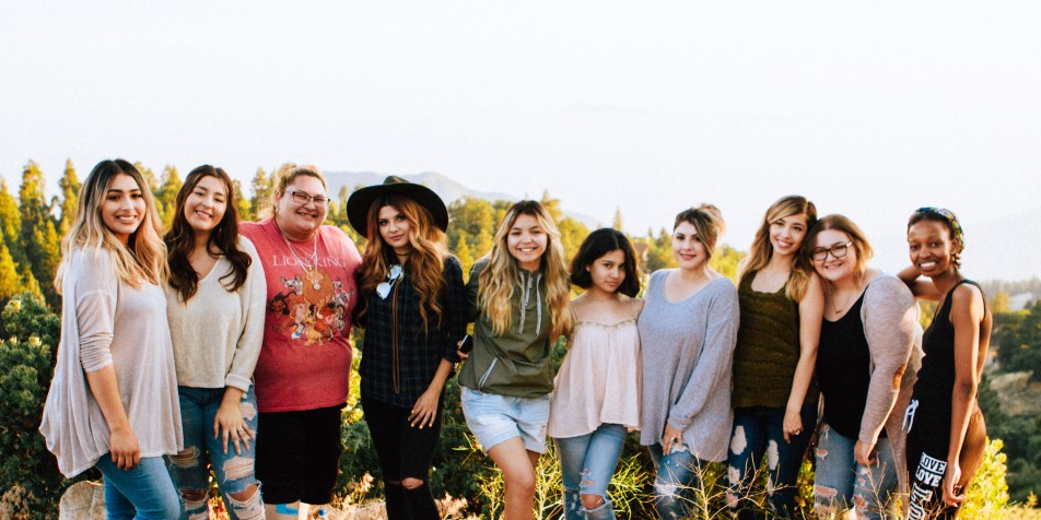 Group of girls standing together outside, facing camera, smiling.