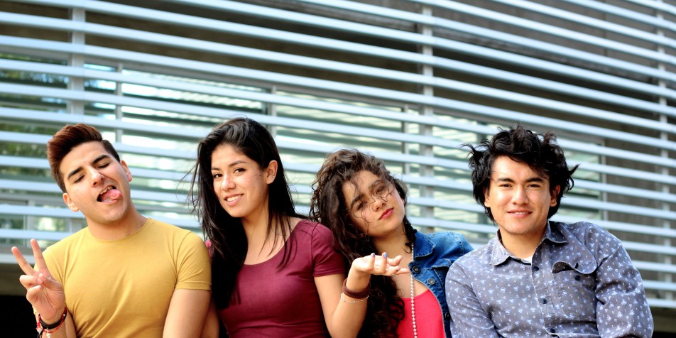 Four youth sitting, making funny faces, laughing.