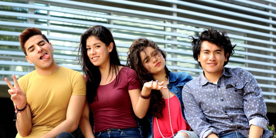 Four youth sitting, making funny faces, laughing.