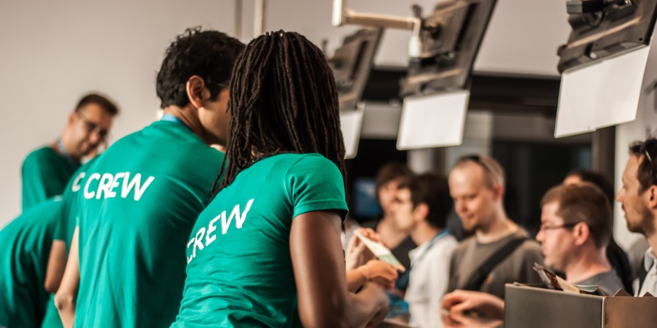 Photo of two young people working an event with "crew" on the back of their shirts.