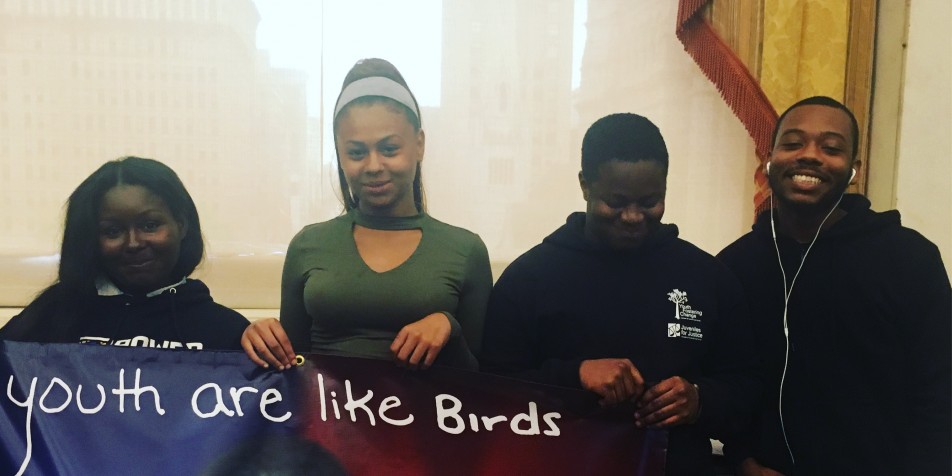 Four youth advocates holding a sign reading "youth are like birds, we need support to fly."