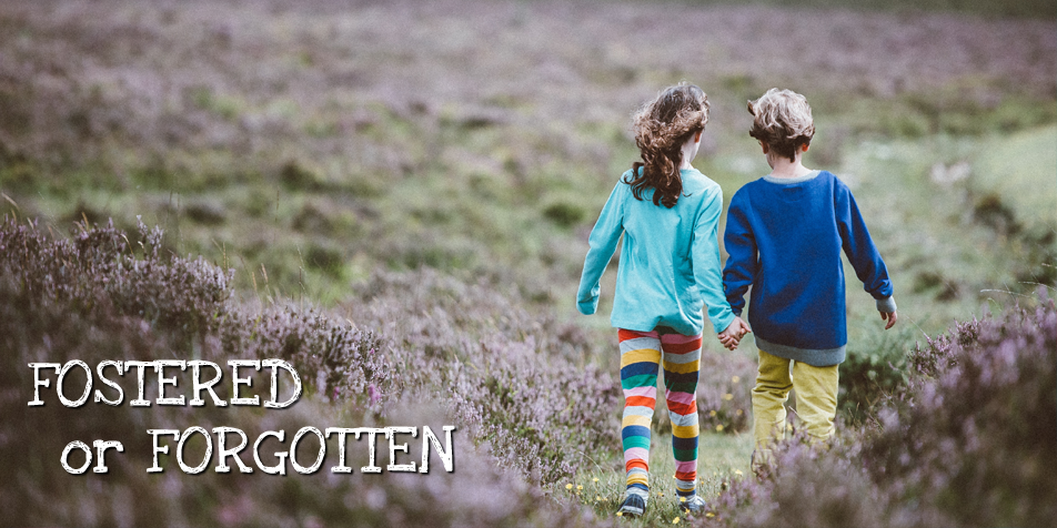 Photo of two young children walking away from camera, holding hands.