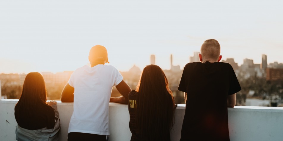 Four youth looking at city skyline during a sunrise.
