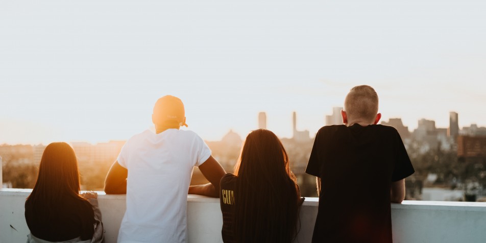 Four youth looking at city skyline during a sunrise.