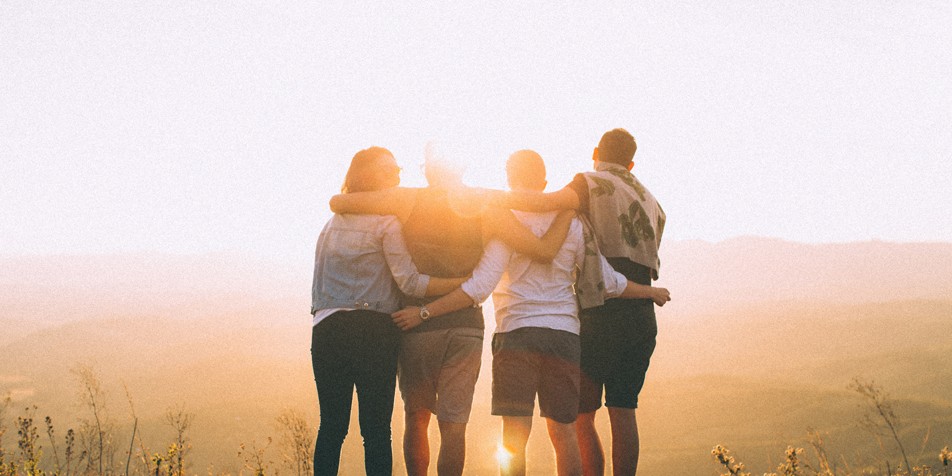 5 people hugging, facing away from camera, during sunrise.