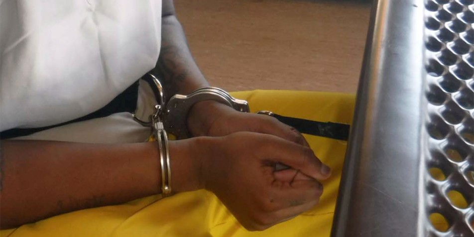 Youth hands in handcuffs, shackled to table.