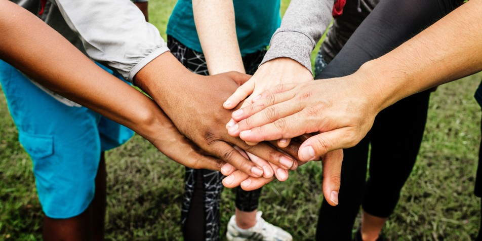 People stacking hands in a "go-team" style gesture.