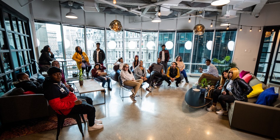 Group of 20 young people hanging out in a lounge area, facing the camera.