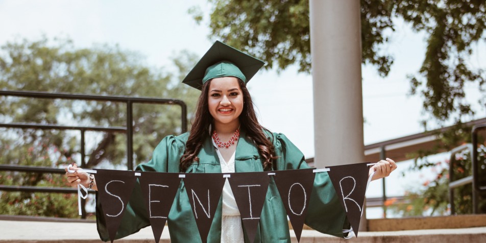 Young latinx woman in graduation cap and gown.