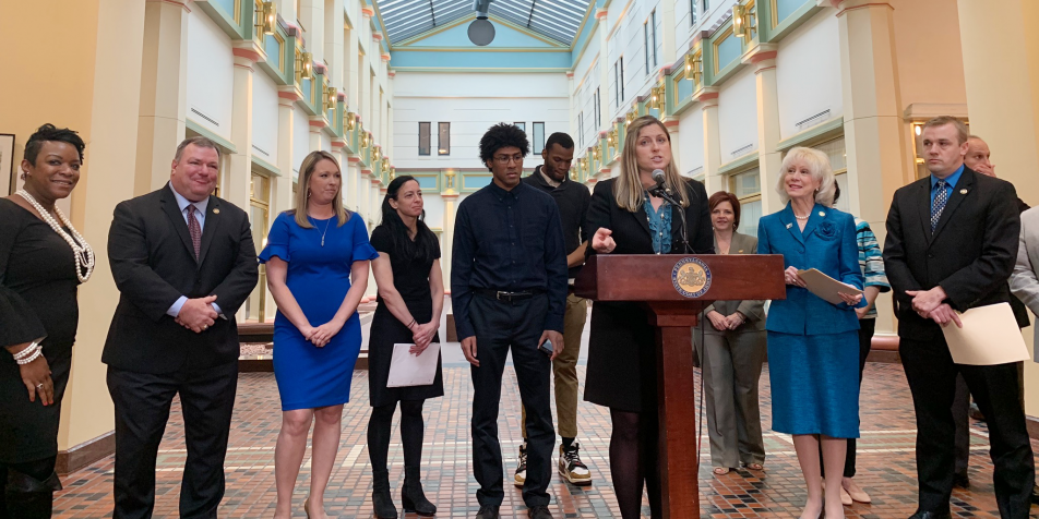 Youth advocates, legislators standing behind podium during press conference.