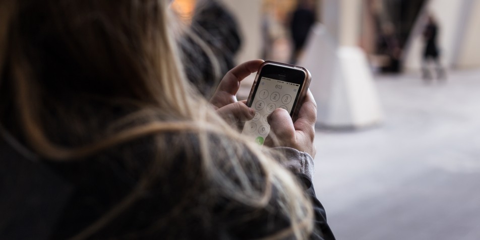 Over-the-shoulder photo of someone dialing a number on a cell phone.