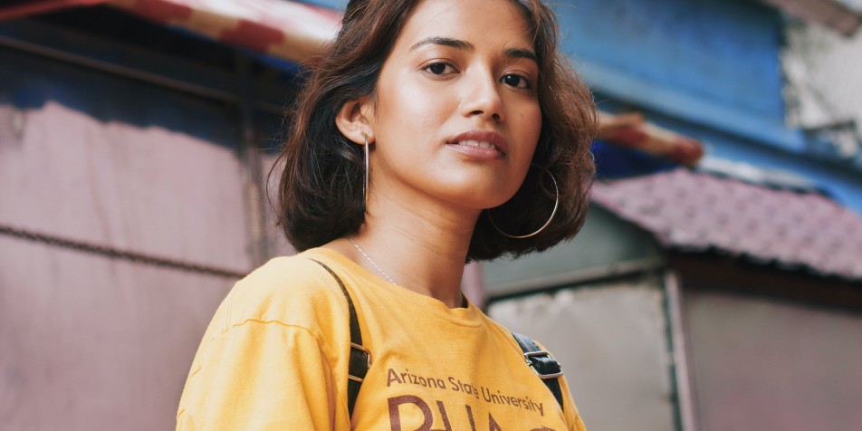 A young woman wearing a backpack and a college tshirt.