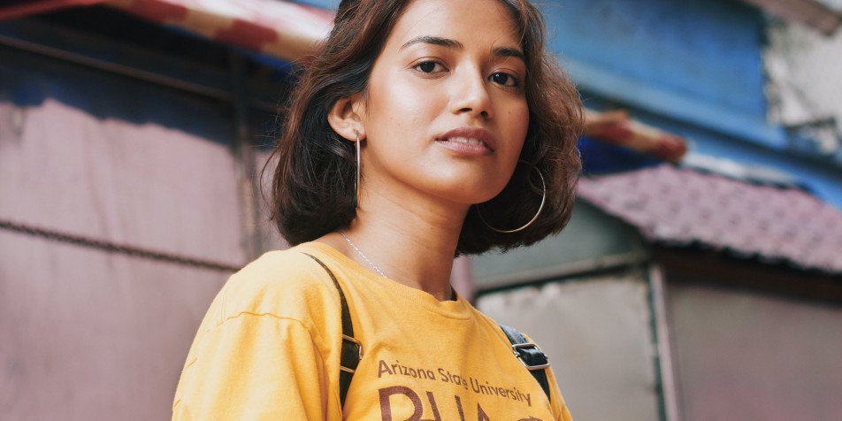 A young woman wearing a backpack and a college tshirt. 