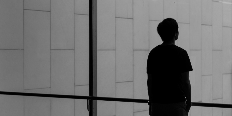 young man looking out of large window 