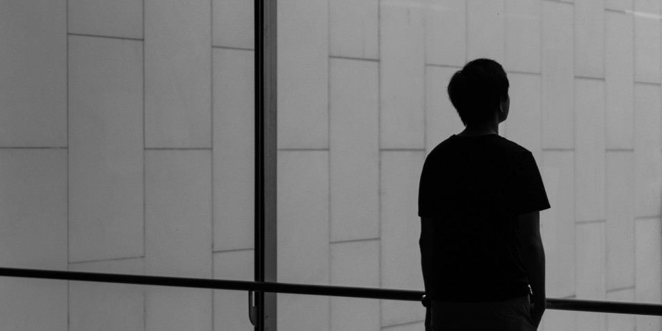 shadow of young man looking out window.