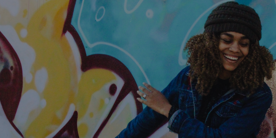 image of young woman dancing in front of graffiti wall.