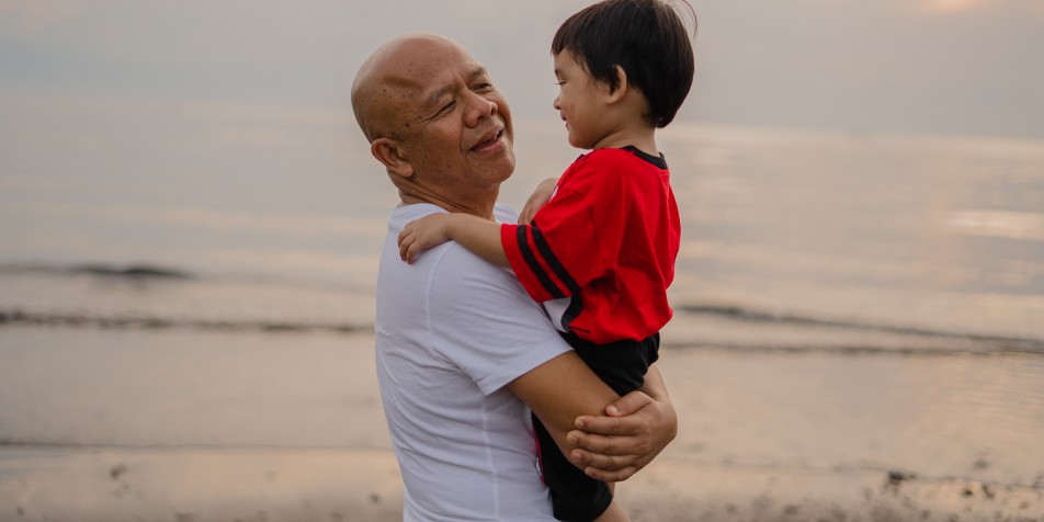 grandpa holding a toddler on the beach