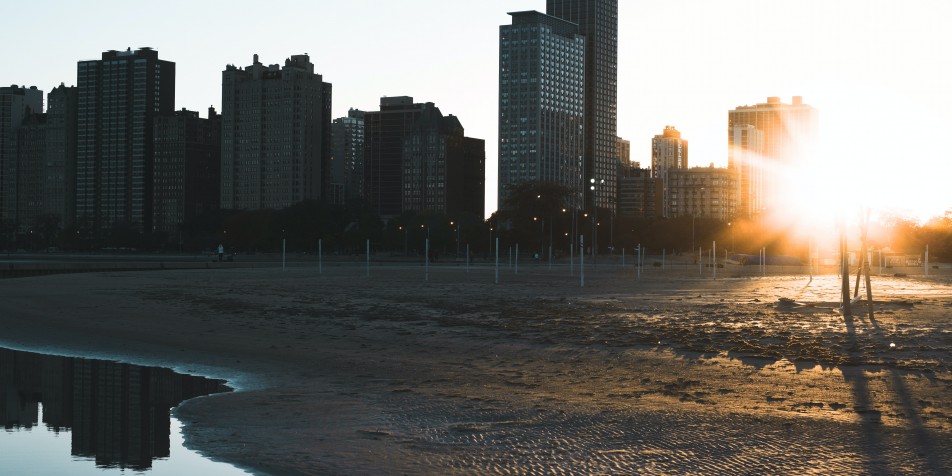 sunrise behind buildings and lake