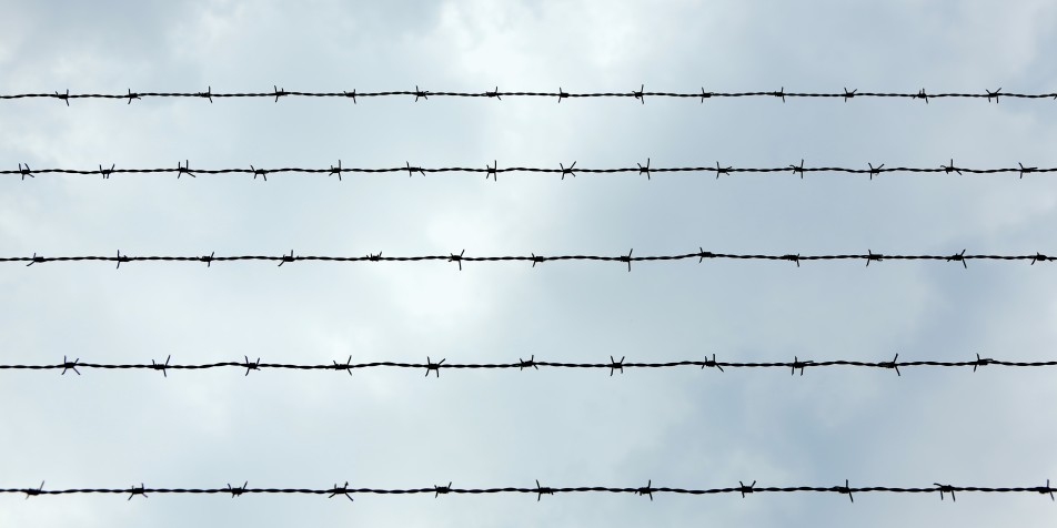 barbed wire against cloudy blue sky