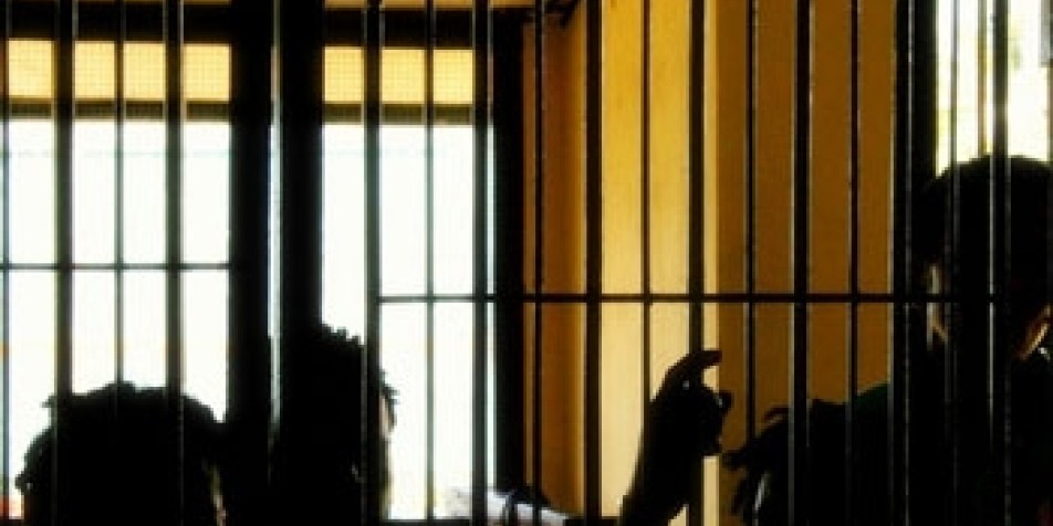 two children behind iron bars in prison with low light