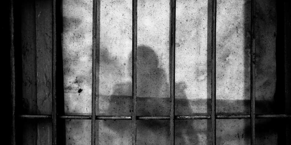 concrete wall with prison bar shadows and silouette 