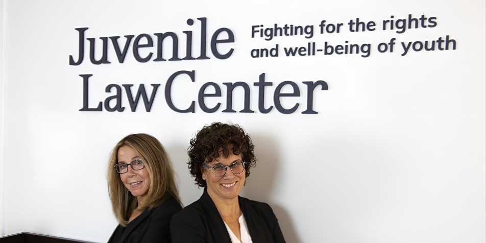 two women standing back to back under a blue logo