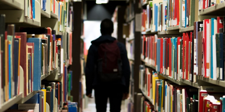 Youth walking down aisle of a library.