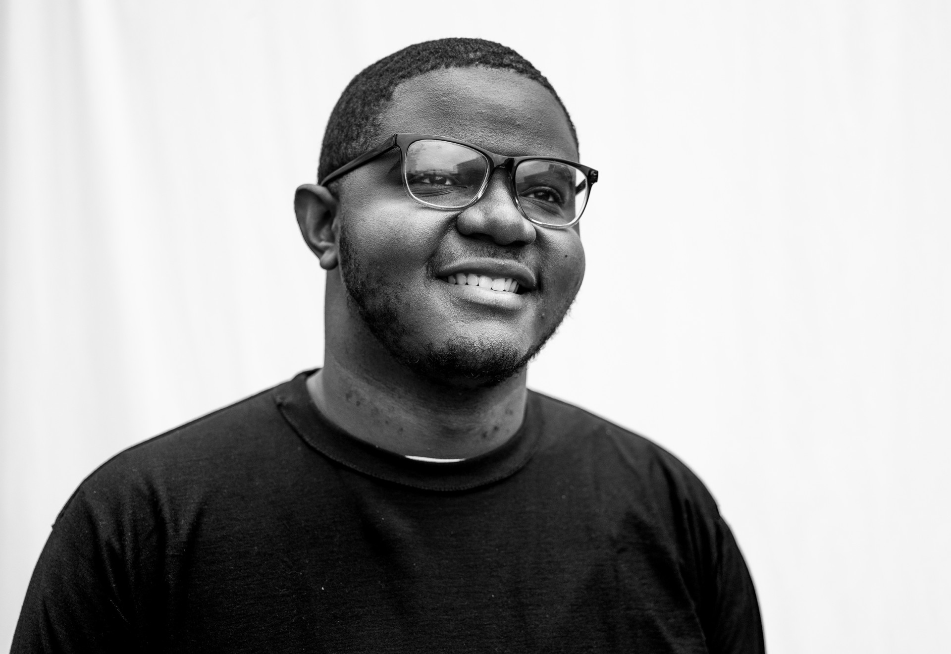 A person wearing glasses and a dark shirt smiling.